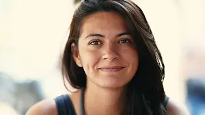 A woman with brown hair and a blue tank top smiles at the camera.
