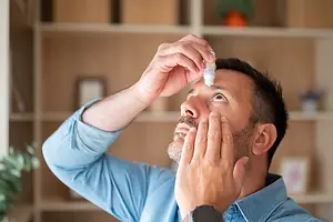 Man applying eye drops while looking upward