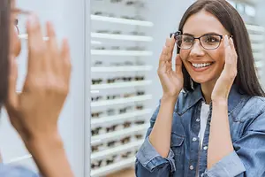 Smiling woman trying on eyeglasses in an optical store
