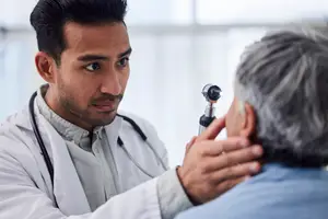 A doctor is examining a patient's ear with a medical instrument