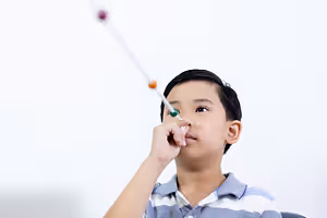A child uses a toy telescope to look at something in front of them