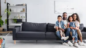 Four people sitting on a couch, two adults and two children, smiling and posing for a photo