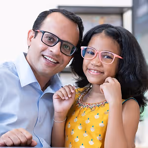 A man and a young girl are smiling and posing for a photo while sitting at a table.