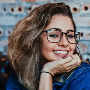 A woman with glasses and a denim jacket smiling at the camera.