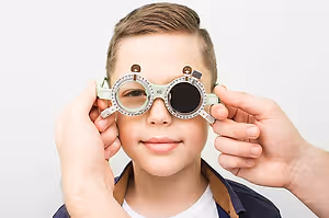 A young boy is wearing a pair of glasses that seem to be for vision testing.
