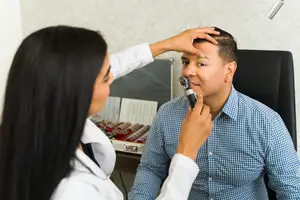 A doctor is examining a man's ear in a clinic.