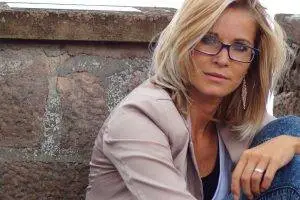 a woman sitting on a wall looking to the right