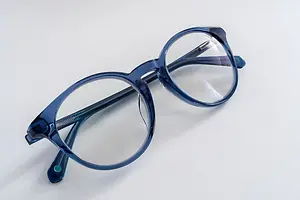 A pair of blue-framed glasses with clear lenses on a white surface