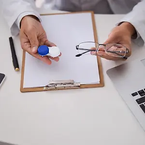 An optometrist examining a patient's eyeglasses and contact lens case.