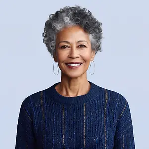 An older woman with curly hair and hoop earrings wearing a navy blue sweater smiles for the camera