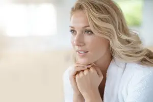 Blonde woman in white bathrobe resting her chin on her hand