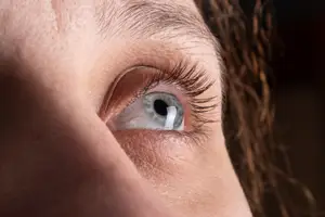 Close-up of a person's eye with long eyelashes and a slight teary look.