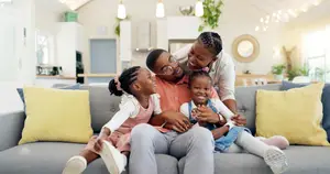 A family of four sitting on a couch and smiling for a photo.