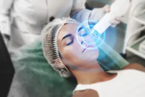 A woman is undergoing a laser treatment on her face in a clinic.
