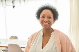 A woman standing inside a room, smiling and looking forward