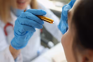 A female doctor examining a patient's face using a medical tool