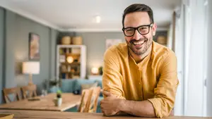 A man is smiling and standing in a room, probably posing for a photo.