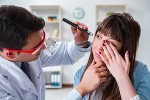 Doctor examining a female patient's eye using a pen light
