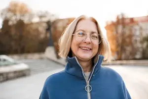 Portrait of a woman standing outdoors with trees in the background.