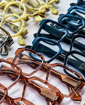 A close up of several pairs of eyeglasses with different designs and colors on a white surface.