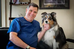 A veterinarian sitting with a dog in a medical office.