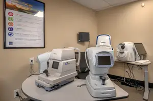 Medical equipment including a CT scanner and other machines on a table in a clinic room.