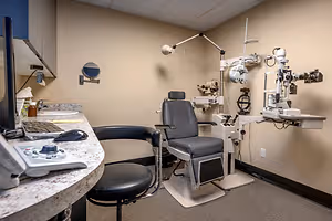 A medical examination room with an eye examination chair and equipment