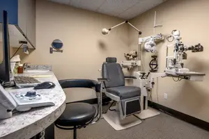 A medical examination room with an eye examination chair and equipment
