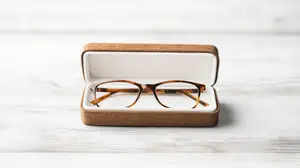 Brown-framed glasses in a brown case on a wooden surface