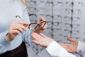 Woman examining glasses with an optician in a store