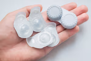 A hand holds several contact lenses in their packaging, showcasing the transparency and design of the lenses.