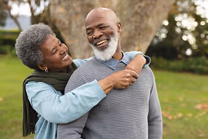 Senior black couple smiling and hugging in a park