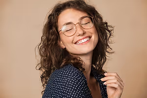 Woman with curly hair and glasses smiling and showing teeth