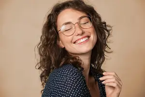 Woman with curly hair and glasses smiling and showing teeth