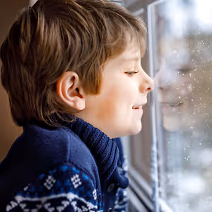 A boy looking out of a window during snowy weather
