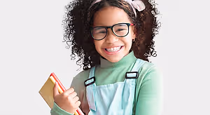 young girl with glasses holding books smiling