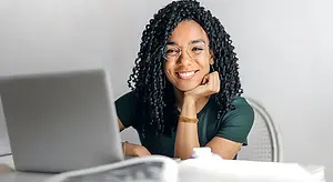 Smiling woman wearing eyeglasses while working on a laptop