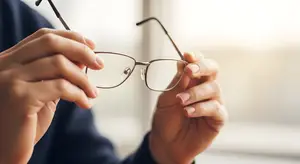A person holding a pair of glasses with a blurry background