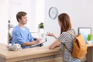 A man in a blue uniform is talking to a woman in a black and white striped shirt in an office.