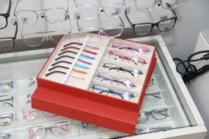 A collection of eyeglasses with various colors and designs are displayed on a shelf inside a shop.