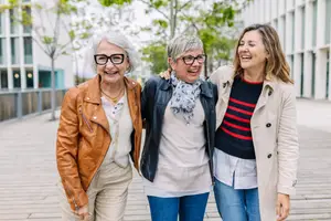 Three women laughing and posing for a photo in a park setting