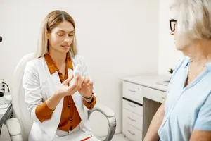 An older woman is consulting with a doctor about her health, perhaps her eyes.