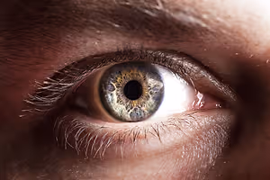 A close up view of a man's eye with a teardrop on the corner of the eye.