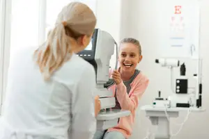 A young girl is getting her eyes examined by an optometrist in a clinic