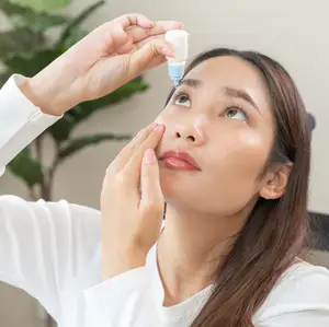A woman putting eye drops in her eye