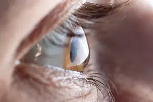 Close-up of an eye with eyelashes and a teardrop on the iris
