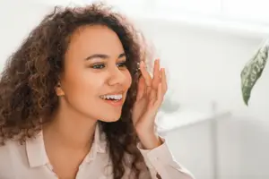 woman smiling and wearing eyeglasses in a room