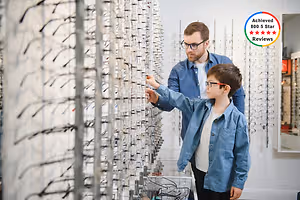 A man and a boy are looking at a display of glasses in a store.