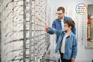 A man and a boy are looking at a display of glasses in a store.