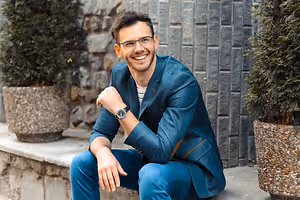 Man in blue suit and glasses sitting outside